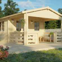A log garden shed with half-glazed double-wide doors and windows, a roofed spacious deck. The roof is in an open gable style, and the surroundings of a garden shed are adorned with plants and flowers.